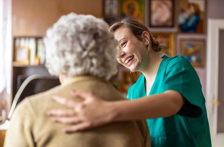 An older adult packing family photos and keepsakes into moving boxes in a bright, organized living room.